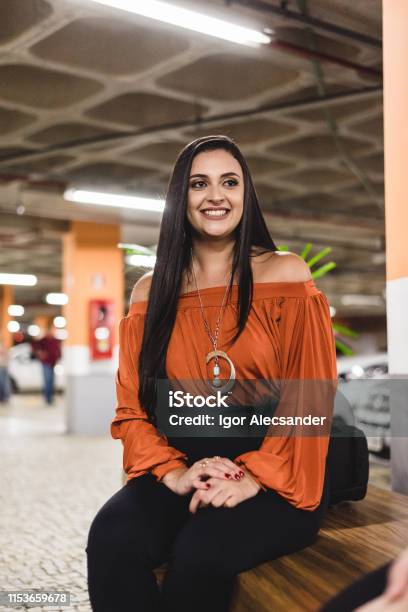 Foto de Mulher Bonita Que Sentase No Lote De Estacionamento Do Aeroporto e mais fotos de stock de Laranja - Descrição de Cor