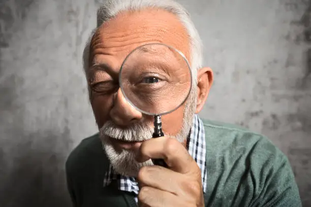 Photo of Mature man looking through a magnifying glass