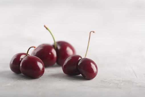 Ugly cherries on the table. Strange shape berries on the gray background with copy space