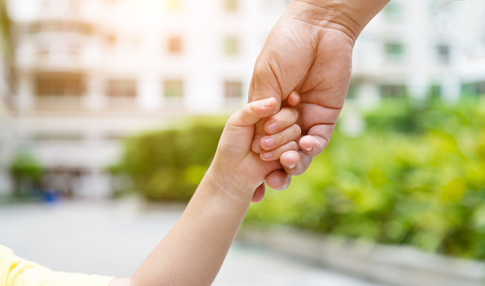 Child's hand holding parent's hand.