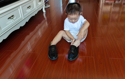 Small boy trying on shoes, that are to big for him.
