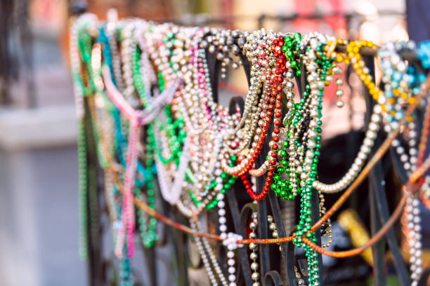 New Orleans, USA closeup of mardi gras beads hanging on fence by colorful building house and nobody on sidewalk New Orleans, USA closeup of mardi gras beads hanging on fence by colorful building house and nobody on sidewalk new orleans mardi gras stock pictures, royalty-free photos & images