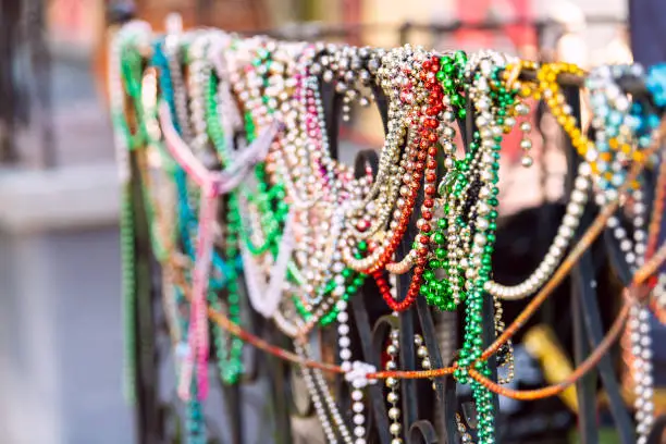 New Orleans, USA closeup of mardi gras beads hanging on fence by colorful building house and nobody on sidewalk