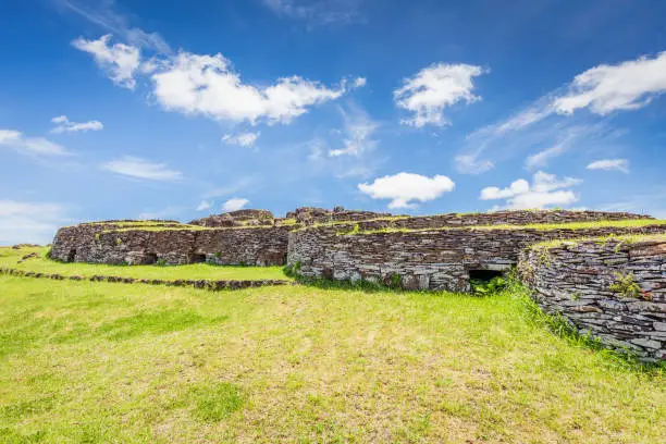 Orongo Stone Village Stone Houses on Easter Island under sunny summer sky. Orongo was the ancient centre of a Birdman Cult. Low, sod covered and windowless round-walled buildings on south-westen tip of volcanic caldera of Rano Kao. Rano Kau, Rapa Nui National Park, Hanga Roa, Easter Island, Chile.