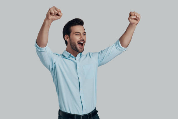 istock I did it! Handsome young man smiling and gesturing while standing against grey background 1153666483