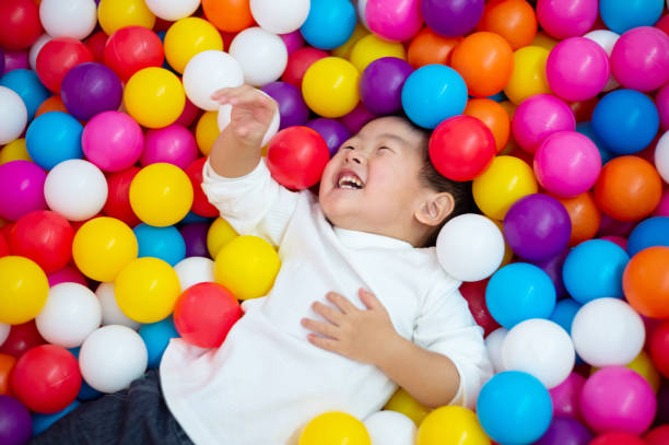 Cute little girl having fun while playing in the ball pool. She is looking at the camera.  