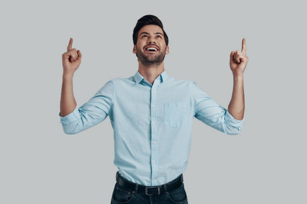 istock Look at that! Handsome young man smiling and pointing copy space while standing against grey background 1153667130