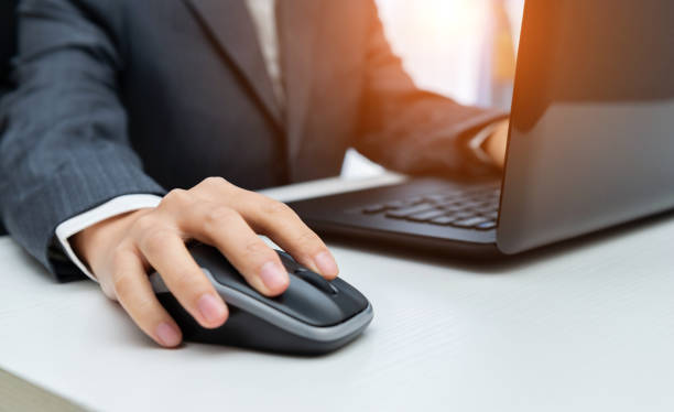 istock Businessman doing some work with hands touching computer mouse and keys of opened laptop 1153667449