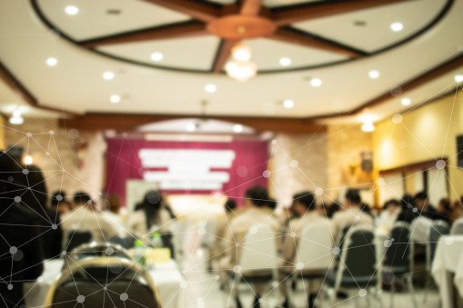 Blurred of speaker on stage IOT network, rear view group audience listens speech lecturer in conference hall or seminar at hotel, business and education meeting concept