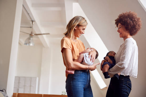 two mothers meeting holding newborn babies at home in loft apartment - mulher bebé imagens e fotografias de stock