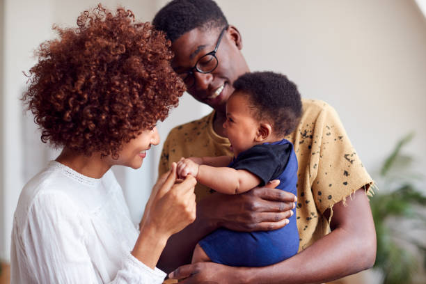 loving parents playing with newborn baby at home in loft apartment - two parent family couple family african ethnicity imagens e fotografias de stock