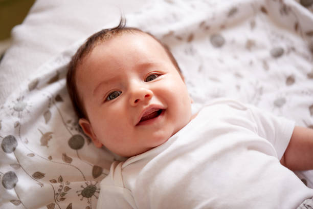 istock Smiling Baby Boy Lying On Bed At Home Smiling At Camera 1153668947