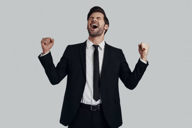 istock Successful man. Handsome young man in full suit gesturing and shouting while standing against grey background 1153669097