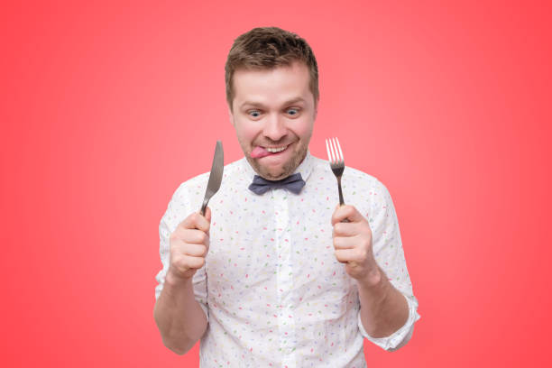 Man holding fork and knife on hand ready to eat, licking lips stock photo