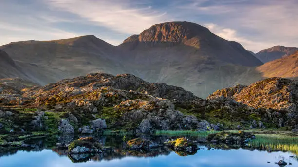 The warm morning light on the lakeland mountain of Great Gable reflecting in Innominate Tarn