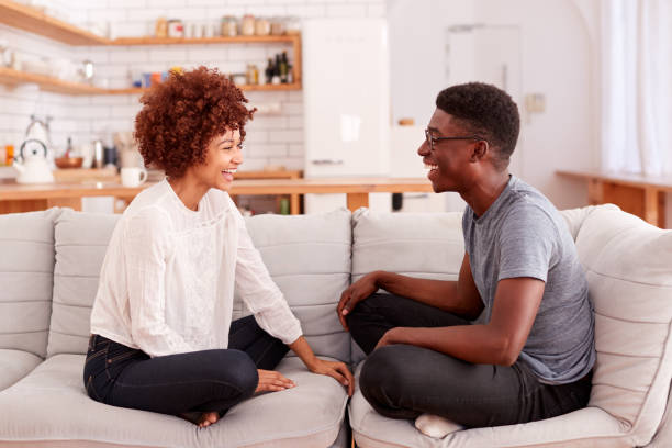 istock Young Couple Relaxing On Sofa At Home Talking Together 1153669662