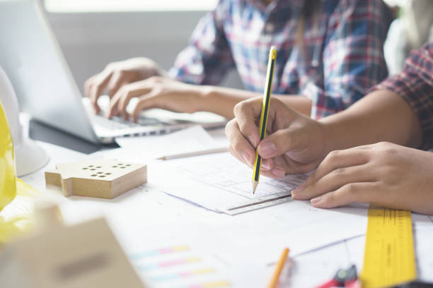 istock colleague architect man working with laptop and blueprints,engineer inspection in workplace for architectural plan,sketching a construction project ,selective focus,Business concept vintage color 1153670616