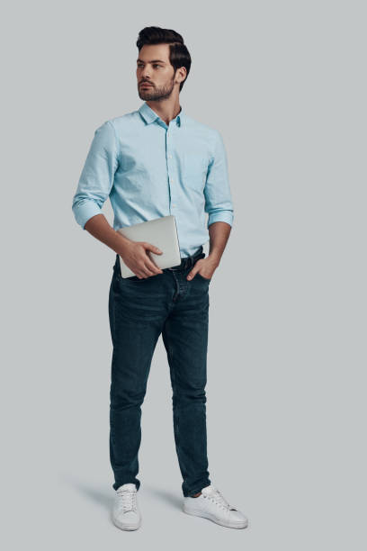istock Young and confident. Full length of young man carrying digital tablet while standing against grey background 1153670801