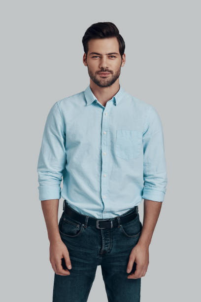 istock Young and handsome. Handsome young man looking at camera and smiling while standing against grey background 1153670924