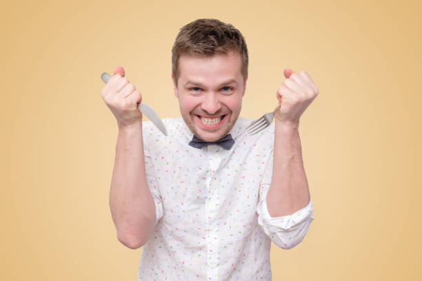 istock Hungry man holding fork and knife on hand to eat 1153671371