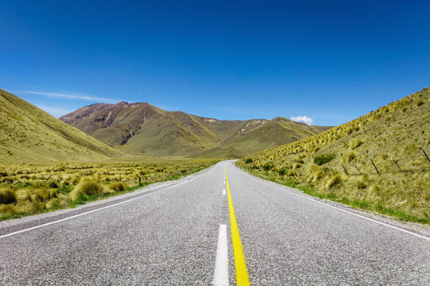 Endless road towards the beautiful hills and green rolling landscape at Lindis Valley - Lindis Pass between Queenstown and Christchurch, Ahuriri Conservation Park, South Island, New Zealand