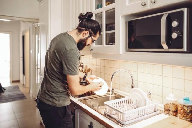 Vaisselle de lavage de jeune homme à la maison - Photo