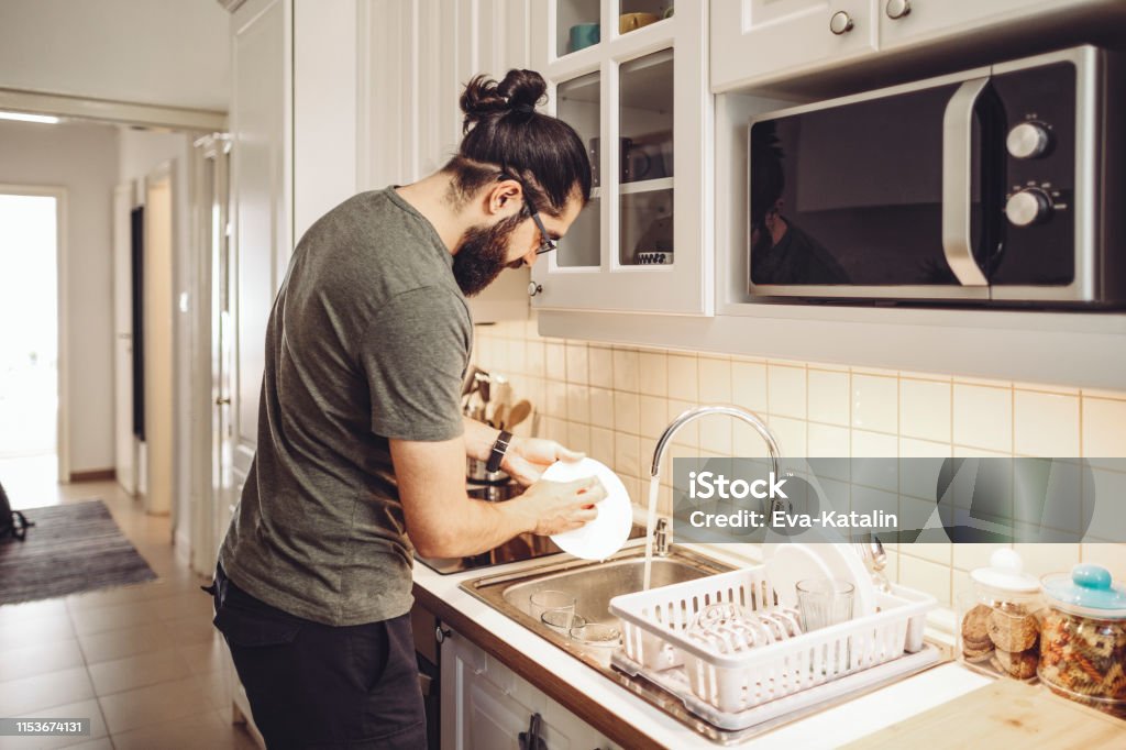 Young man washing dishes at home Men Stock Photo