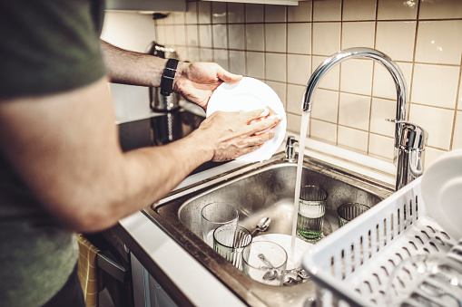 Young man washing dishes at home
