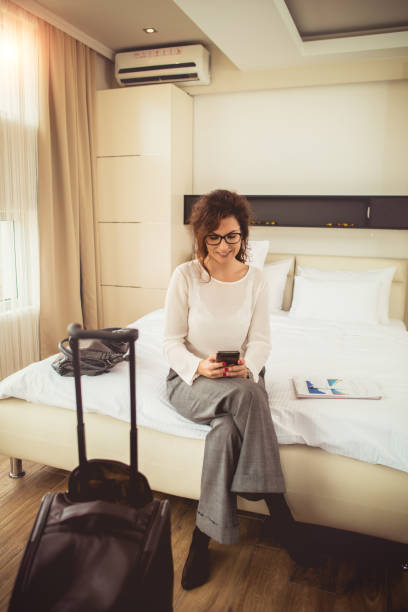 istock Businesswoman using phone in hotel room 1153676785