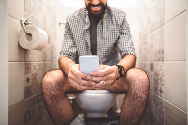 uomo che usa uno smartphone mentre è seduto in bagno - indian culture business businessman financial advisor foto e immagini stock