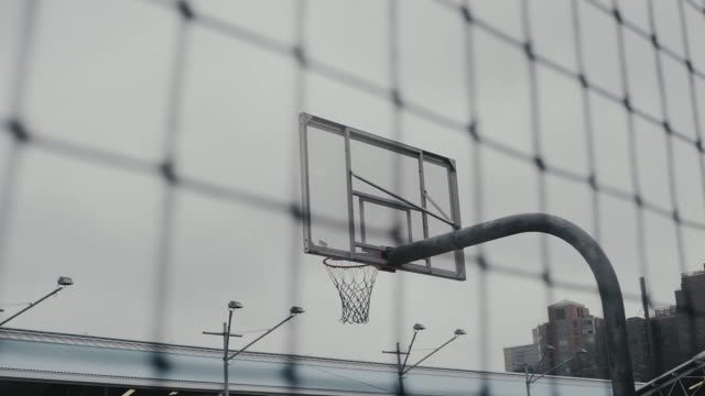 Basketball hoop seen from fence against sky