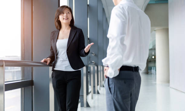 istock Two young business people chatting with each other at office corridor 1153681666