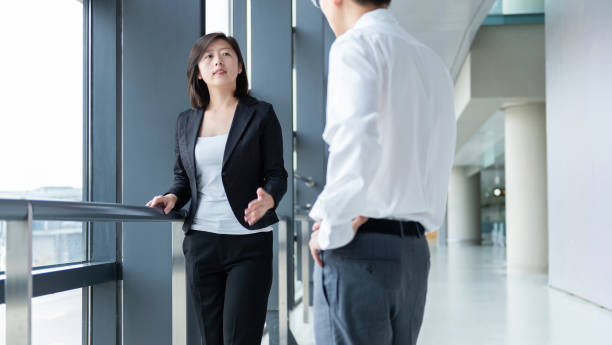 istock Two young business people chatting with each other at office corridor 1153682770