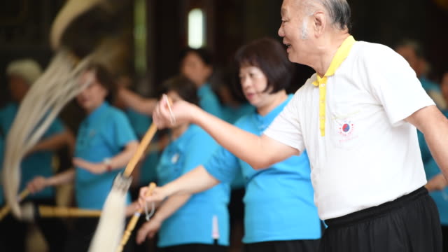 Seniors doing Tai Chi exercise together in temple