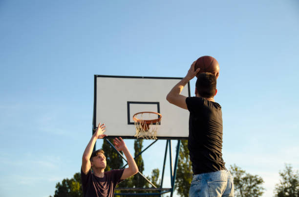 istock Teens playing basketball outdoors 1153684482
