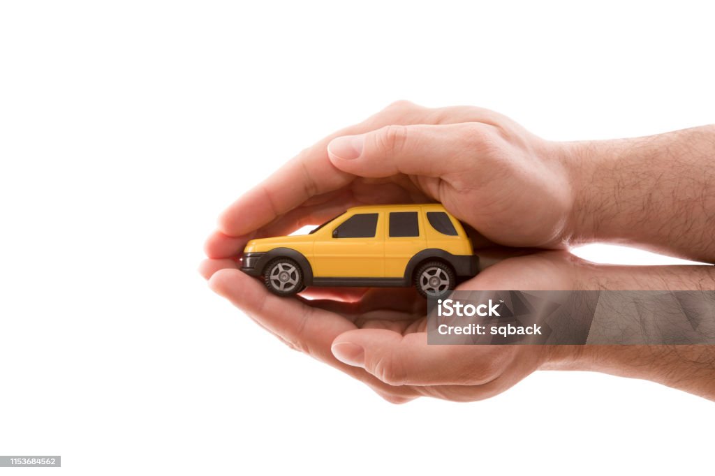 Car protection. Small yellow car covered by hands isolated on white background with clipping path Car Stock Photo