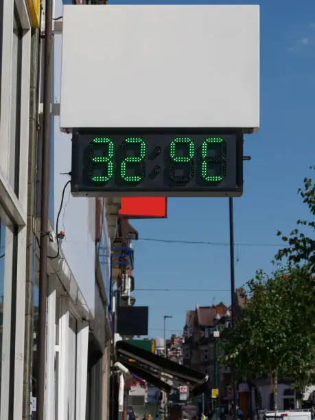 Photo of Street digital thermometer displaying a temperature of 32 degrees celsius. Heat wave concept.