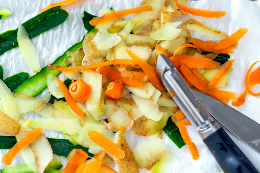 Cáscaras vegetales de zanahorias, patatas y calabacín recién pelados con un pelador photo