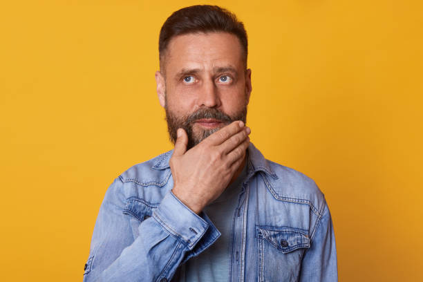 istock Thoughtful pensive bearded man posing with peaceful facial expression, touching his chin with one hand, looking somewhere up, having lots of new thoughts and ideas. People, life and emotions concept. 1153686281