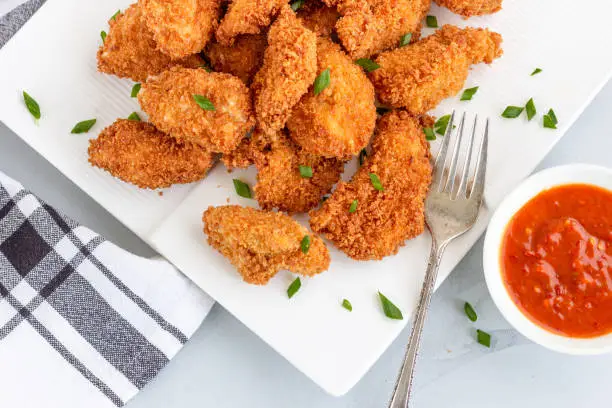 Chicken Nuggets on a Plate Served with Red Sauce on White Background. Popular American Fried Food, Snack, Fast Food, Fried Chicken Dish.