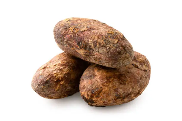 Pile of three roasted unpeeled cocoa beans isolated on white.