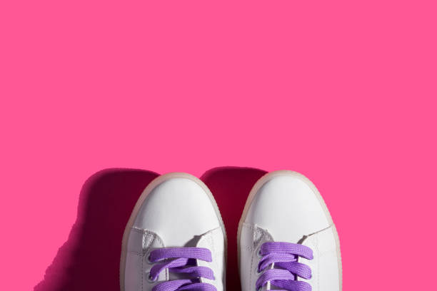 istock White sneakers with purple laces on bold pink 1153687283