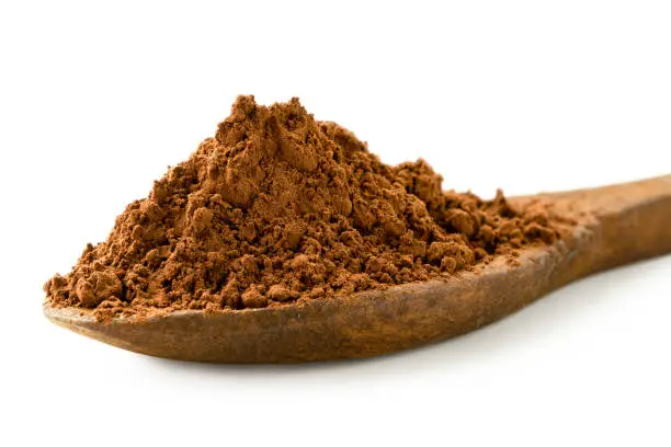 Detail of cocoa powder on a wooden spoon isolated on white.
