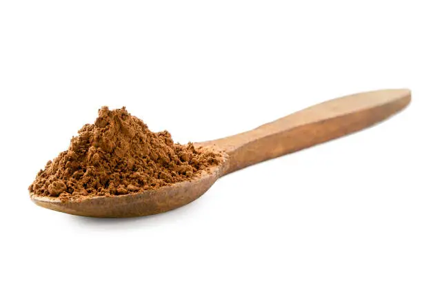 Cocoa powder on a wooden spoon isolated on white.