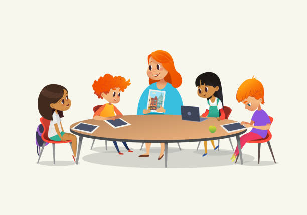 Redhead female teacher showing picture to children sitting around round table at class with laptop and tablet pc. Kids using gadgets during lesson at primary school. Colorful vector illustration. Redhead female teacher showing picture to children sitting around round table at class with laptop and tablet pc. Kids using gadgets during lesson at primary school. Colorful vector illustration kids classroomv stock illustrations