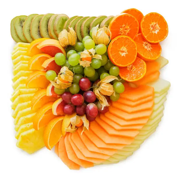 Mix of arranged freshly cut tropical and citrus fruit isolated on white from above.