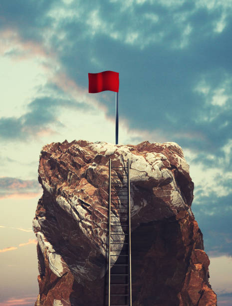 Ladder on a mountain peak leading to a red flag. stock photo