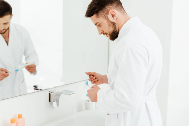 istock selective focus of handsome bearded man holding toothpaste and toothbrush in bathroom 1153687990