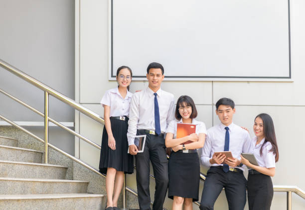 istock Students stand and smile on stairs with white billboard 1153689502