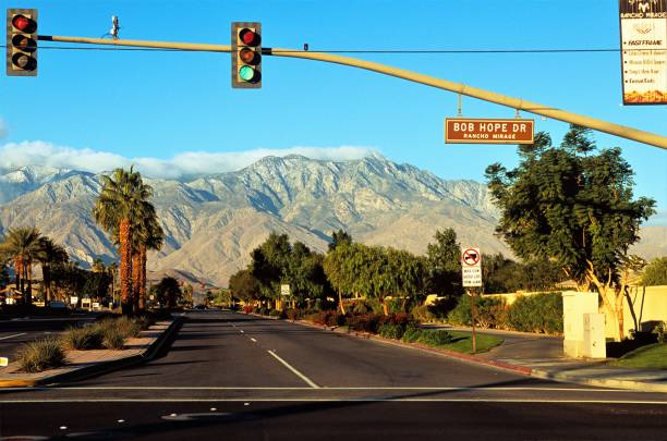 Bob Hope Drive intersection with Gerald Ford Drive at sunrise in Coachella Valley in Rancho Mirage California USA. With Mount San Jacinto in background. An 11,000 foot tall granite massif jutting straight up from desert floor. Part of the San Andreas Geologic Fault Line. A tranquil morning in a desert paradise. cruce de la impulsión de bob hope con la impulsión de gerald ford en sunrise en el valle de coachella en rancho mirage california usa con el monte san jacinto en el fondo un macizo del granito de 11.000 pies que sobresale directamente hacia arriba parte